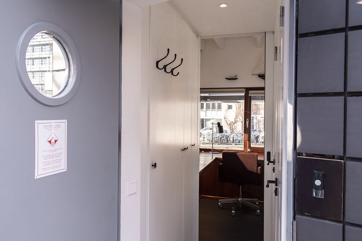 A modern office space with a white door, a round window, and a view of the outside.