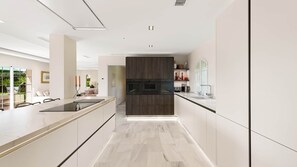 A modern kitchen with a central island, built-in appliances, and a view to a dining area.