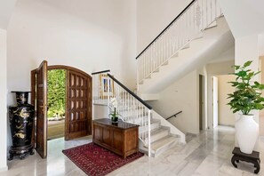 A spacious foyer with a marble floor, a wooden cabinet, a red rug, and a staircase with white railings. - Luxury Golden Mile Villa Marbella With Pool (Marbella)
