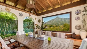A dining area with a wooden table, chairs, and a view of a mountainous landscape through a large window.