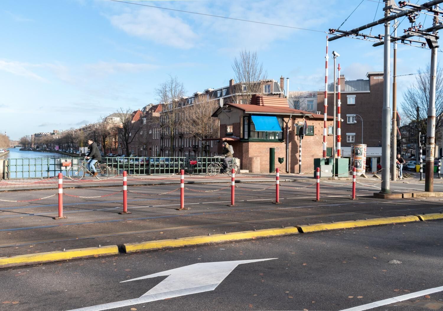 Vista de la calle con un carril para bicicletas, un paso de peatones y un edificio con toldo azul.