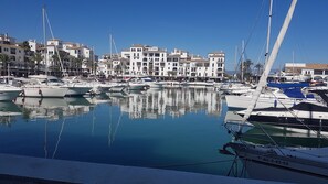 A marina with boats docked, a clear sky, and buildings in the background. - Modern Duquesa 2 Bed,Outstanding view of sea/golf (Duquesa)