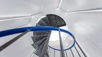 Una escalera de caracol con barandilla metálica y una cuerda de seguridad azul.