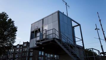 Un edificio moderno con fachada de vidrio, una escalera de metal y una antena en la azotea.