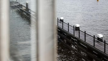 A pier extending into calm water with a metal railing and white bollards.