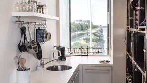Una cocina moderna con un amplio ventanal, electrodomésticos de acero inoxidable y vistas a un paisaje urbano.
