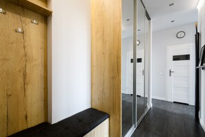 A hallway with wooden paneling, a bench, and a glass door leading to another room. - Labo Apartment Tamka (Warsaw)