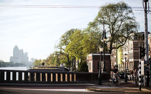 A riverside walkway with a bridge, trees, and historic buildings.