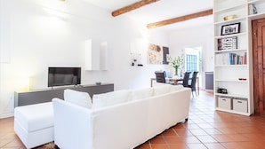 A modern living room with a white sofa, a TV, and a bookshelf. - L'angolo segreto nel pieno centro di Ferrara (Ferrara)
