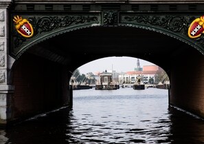 Un pont de pierre orné de sculptures et portant deux blasons.