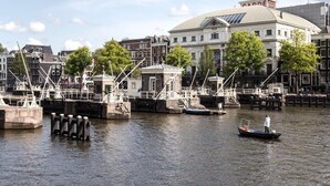 A canal with boats, a white building with a dome, and a theater in the background. - SWEETS - Amstelschutsluis (Amsterdam)