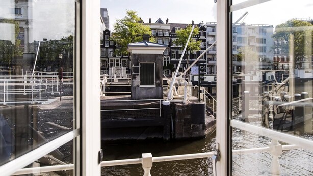 A canal view with traditional buildings, a small dock, and a waterway. - SWEETS - Amstelschutsluis (Amsterdam)