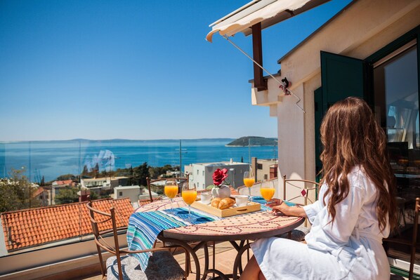 Un balcon avec une table préparée pour le petit-déjeuner, offrant une vue sur la côte.