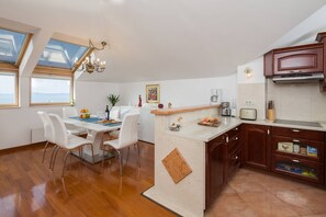 Une cuisine moderne dotée d’un îlot central, de meubles en bois et d’un coin repas avec des chaises blanches.