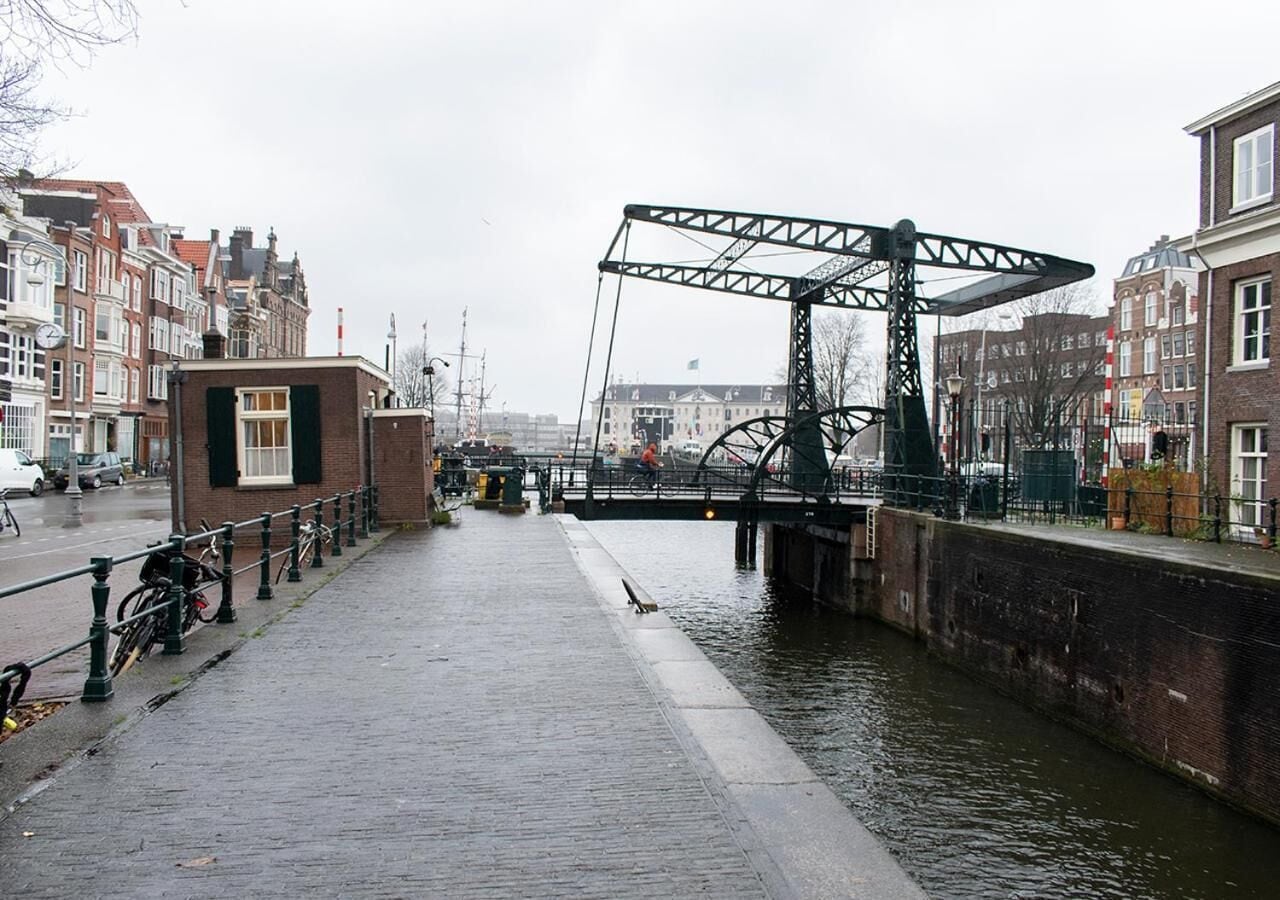 A canal with a bridge, a row of bicycles, and buildings along the water's edge.
