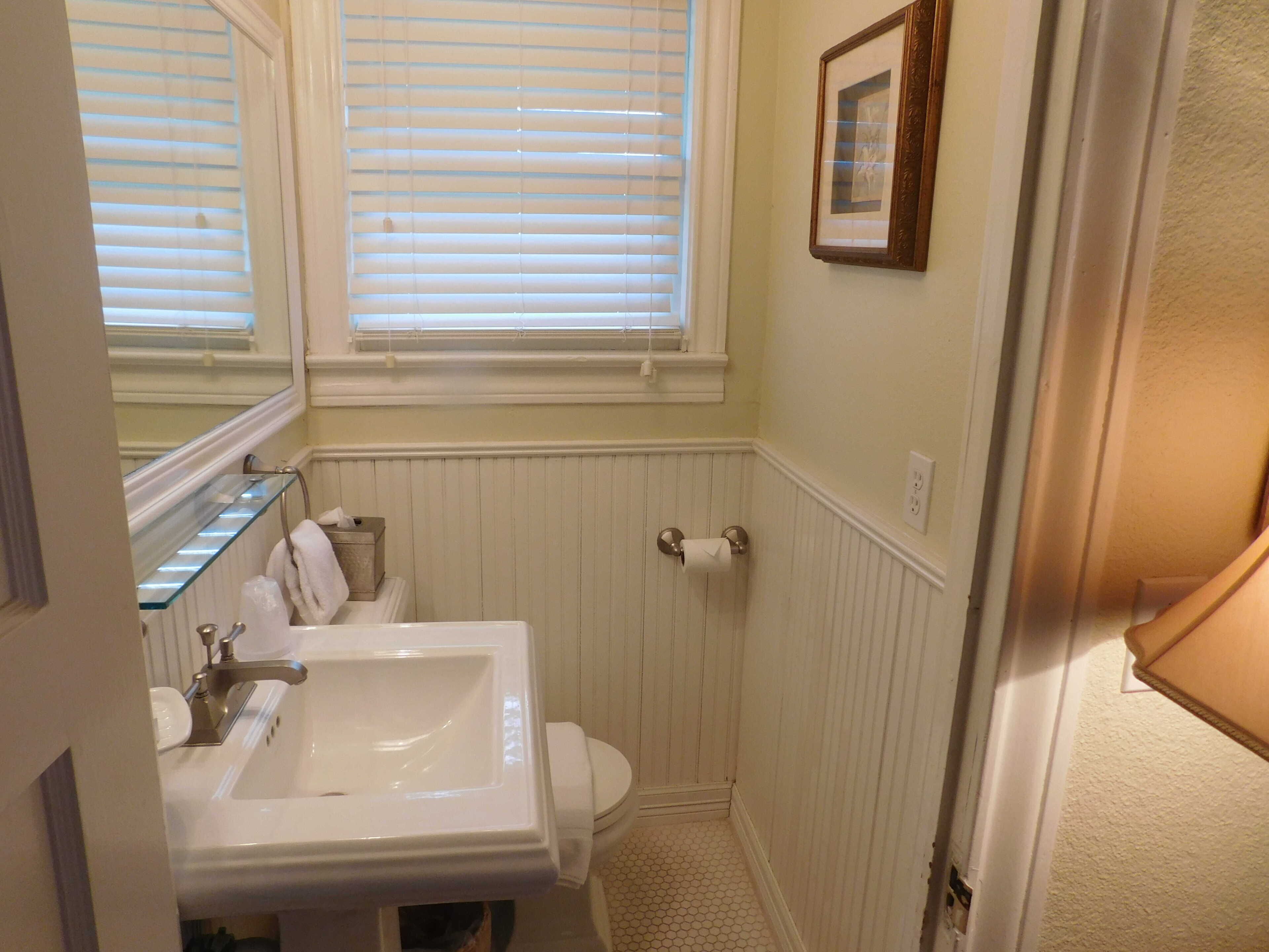 A bathroom with a white sink, toilet, and window blinds.