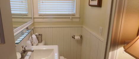 A bathroom with a white sink, toilet, and window blinds.