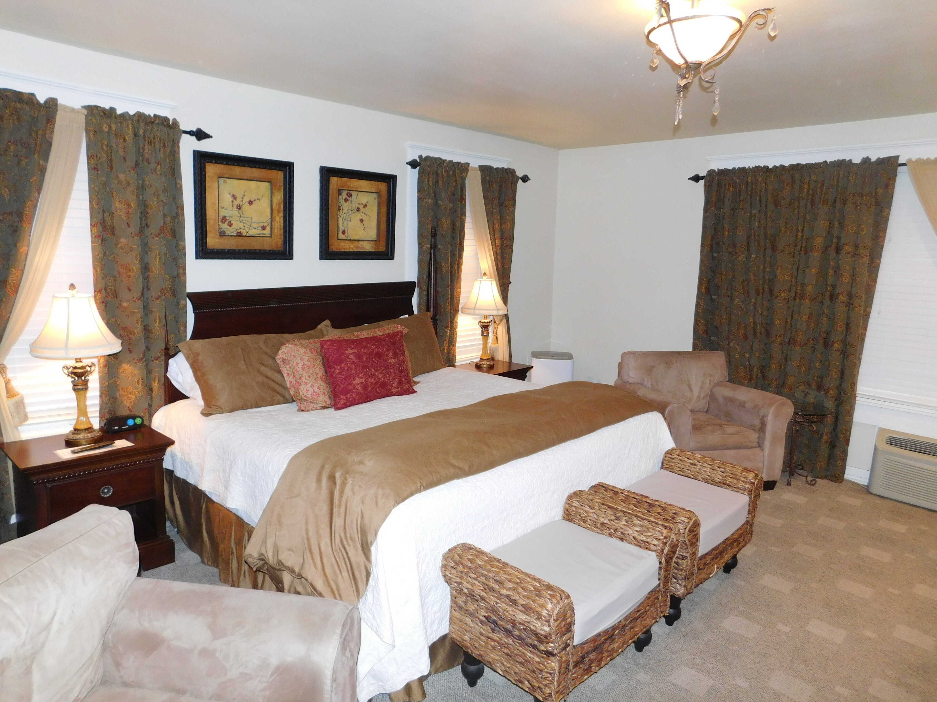 A hotel room with a large bed, two bedside tables with lamps, a chair, and a small table.