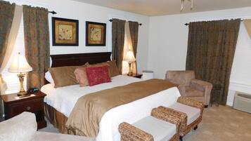 A hotel room with a large bed, two bedside tables with lamps, a chair, and a small table.