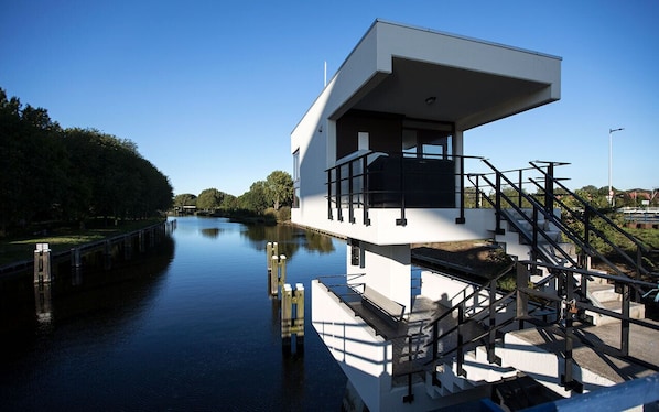 A modern building with a flat roof, large windows, and a staircase leading to an upper level. - SWEETS - Meeuwenpleinbrug (Amsterdam)