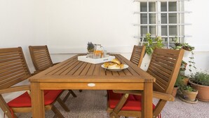 A wooden table with red cushions, surrounded by wooden chairs, and a tray with food and drinks. - Apartment Dinka with terrace (Split)