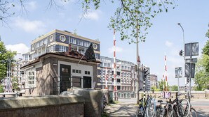 A building with a brick facade, a balcony, and a flag. - SWEETS - Van Hallbrug (Amsterdam)