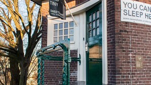 A brick building with a green door and a sign that reads "You can sleep here." - SWEETS - Willemsbrug (Amsterdam)