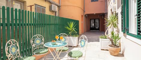 A courtyard with outdoor seating, a potted plant, and a building entrance.