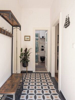 A hallway with a wooden bench, a potted plant, a patterned floor, and a doorway leading to a bathroom. - Luxury apartment Toni with patio in the heart of Split (Split)