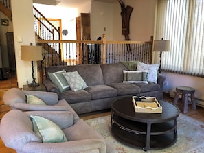 A living room with a grey sofa, two armchairs, a coffee table, and a staircase. - Frisco Townhome, over 2000 squarefeet, Two family rooms, Monthly rates available (Frisco)