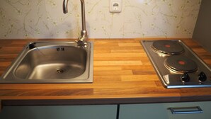 A kitchen with a stainless steel sink, wooden countertop, and a gas stove.