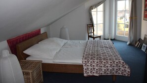 A bedroom with a bed, a chair, a window, and a door.