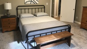 A bedroom with a bed, nightstands, a bench, a door, and a wall-mounted picture. - Nagawicka Woods-Beautiful Lake Country Ranch Home (Delafield)