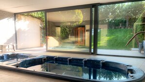 Tinaco moderno en un interior con grandes puertas de cristal que dan a un jardín.