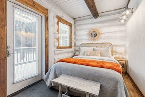 A log cabin bedroom with a bed, bench, and a sunburst wall decoration.