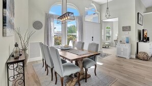 A dining area with a wooden table, grey upholstered chairs, and a chandelier. - Lovely Pet-friendly Waterfront Home With Pool and Dock (Marco Island)