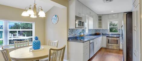A modern kitchen with white cabinets, a granite countertop, and a stainless steel oven.