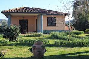 A house with a tiled roof, a porch, and a garden with a large pot. - Agriturismo La Talpa (Manciano)