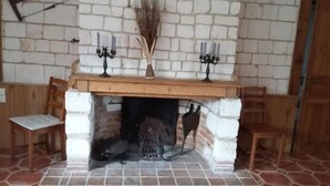 A fireplace with a white brick surround, two candelabras, and a vase with dried plants. - Domaine de collen (Lépine)