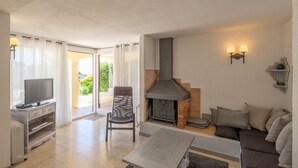 Un salon avec une cheminée, un téléviseur, un canapé et un fauteuil.