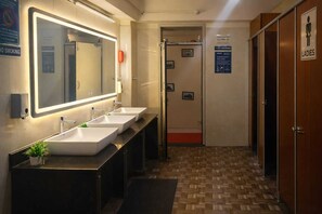 A hotel bathroom with three sinks, a large mirror, and a 'No Smoking' sign.