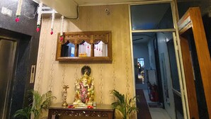 Une pièce avec un luminaire au plafond, un miroir, une petite statue posée sur une table et deux plantes en pot.