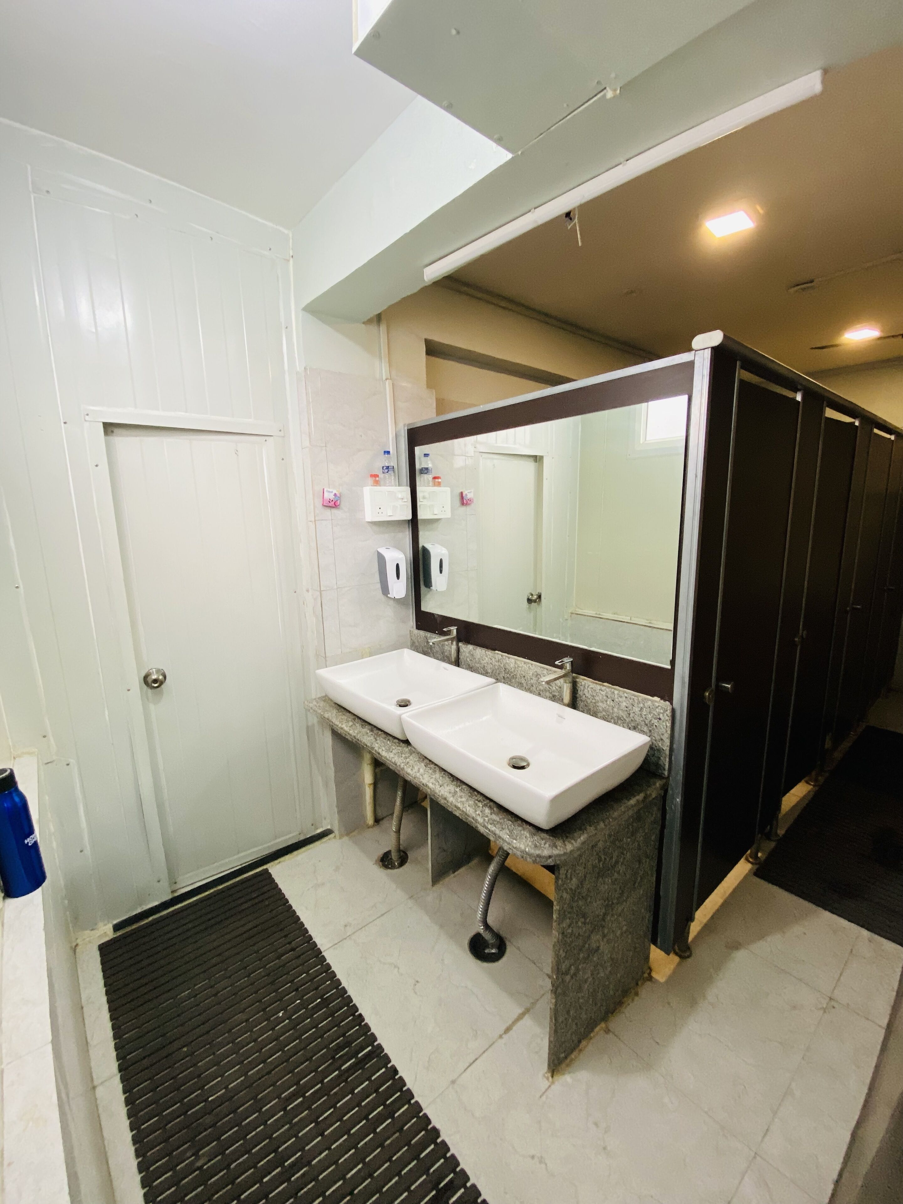 A bathroom with two sinks, a mirror, and a door.