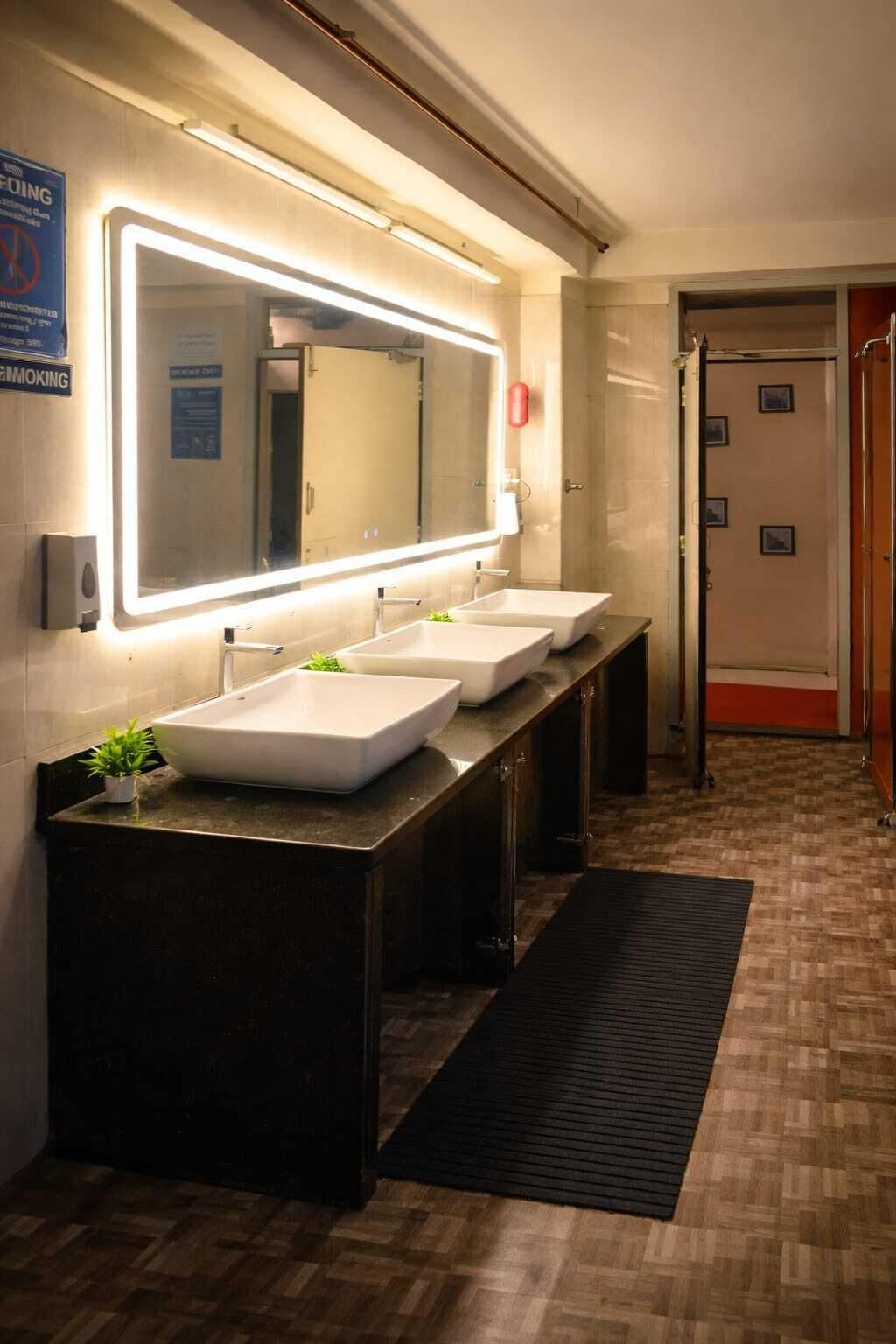 A modern bathroom with two sinks, a large mirror, and a black mat on the floor.