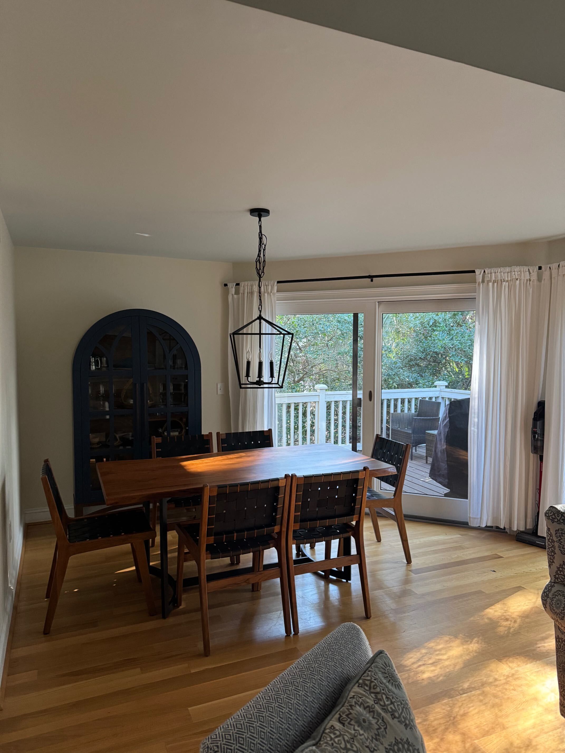 A dining area with a wooden table and chairs, a blue cabinet, and a view of the outdoors.