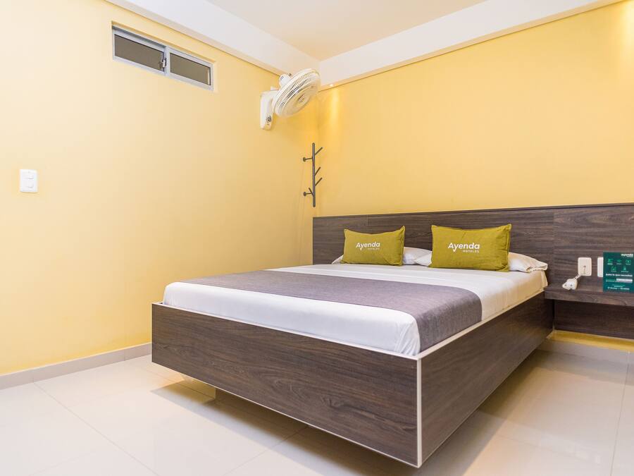 A modern bedroom with a wooden bed, two pillows, a bedside table, and a wall-mounted air conditioner.