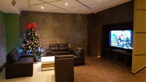 Una sala moderna con un televisor de pantalla plana grande, un árbol de Navidad y sofás de cuero.