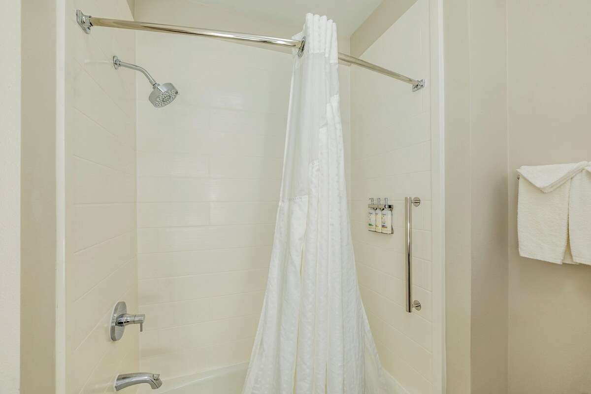 A shower with a glass door, a towel rack with a towel, and a showerhead.