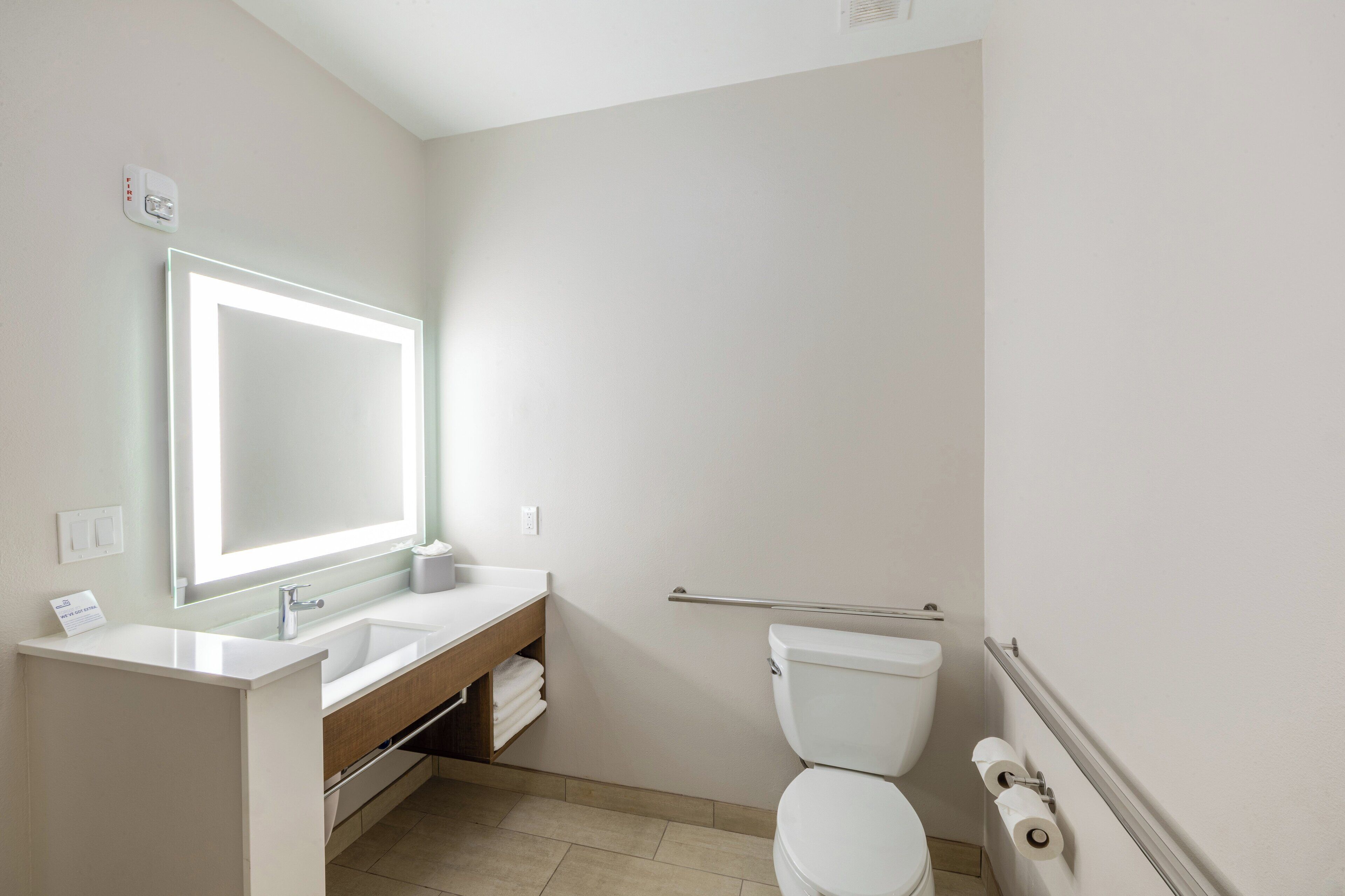 A modern bathroom with a white sink, mirror, and toilet.
