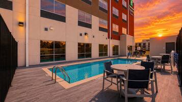 Un hotel con piscina, mobiliario exterior y vistas al atardecer.